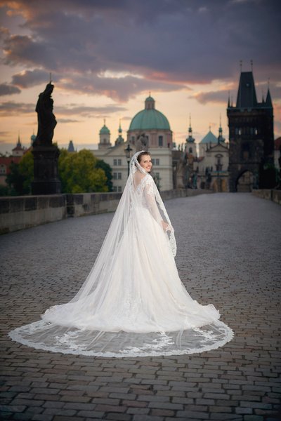 Adele posing in wedding dress on Charles Bridge at sunrise