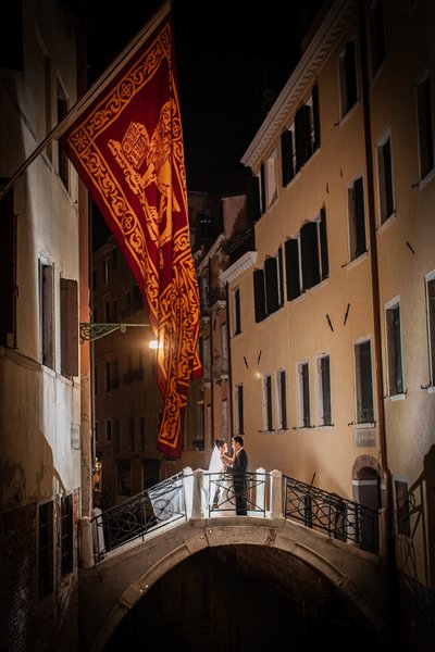 Couple enjoy the canals of Venice under Standard of Saint Mark