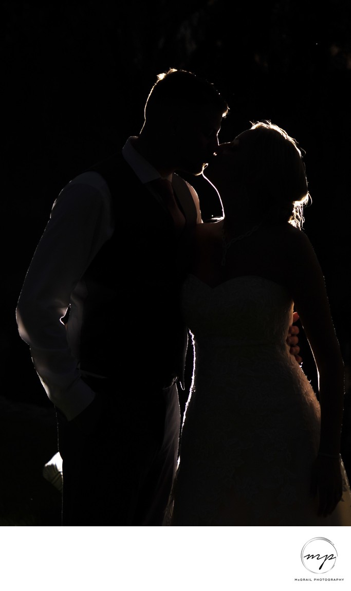Silhouette of Bride and Groom Sharing a Kiss