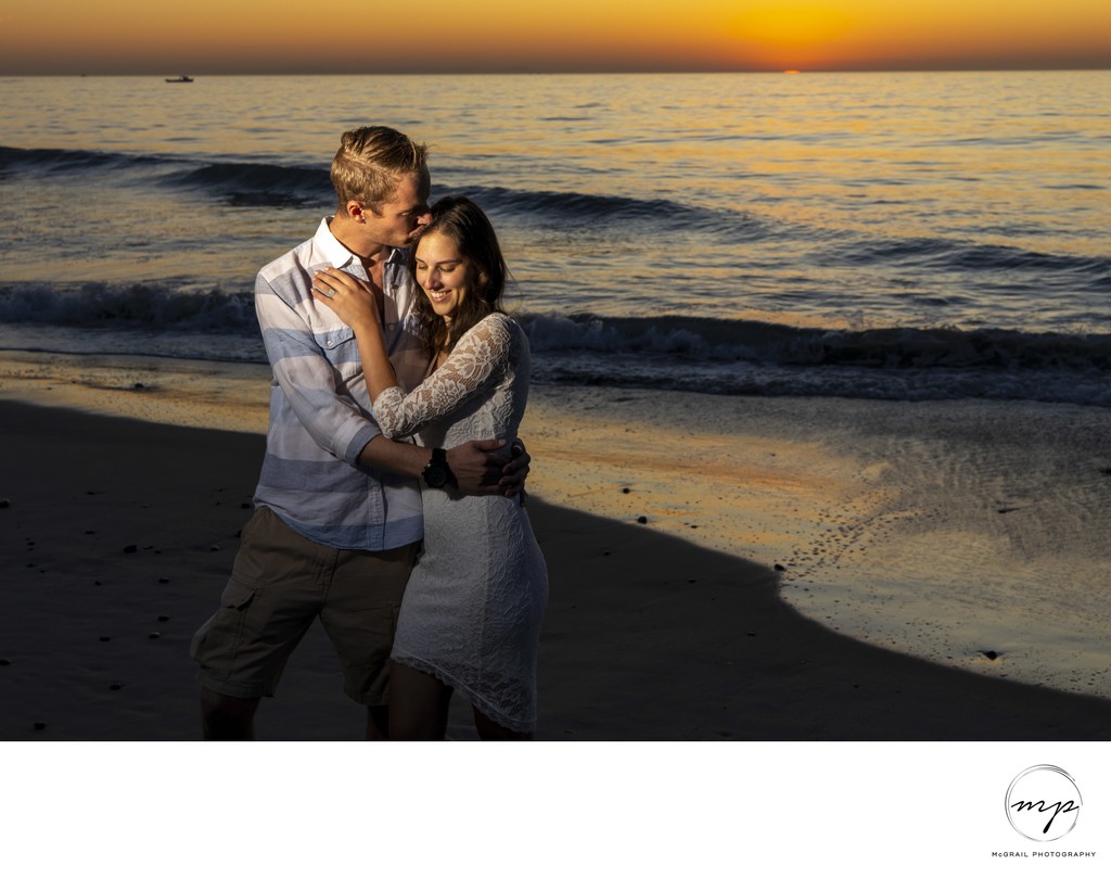 romantic engaged couple by the waves during sunset