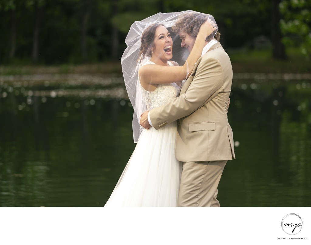 bride and groom laughing under bride's veil