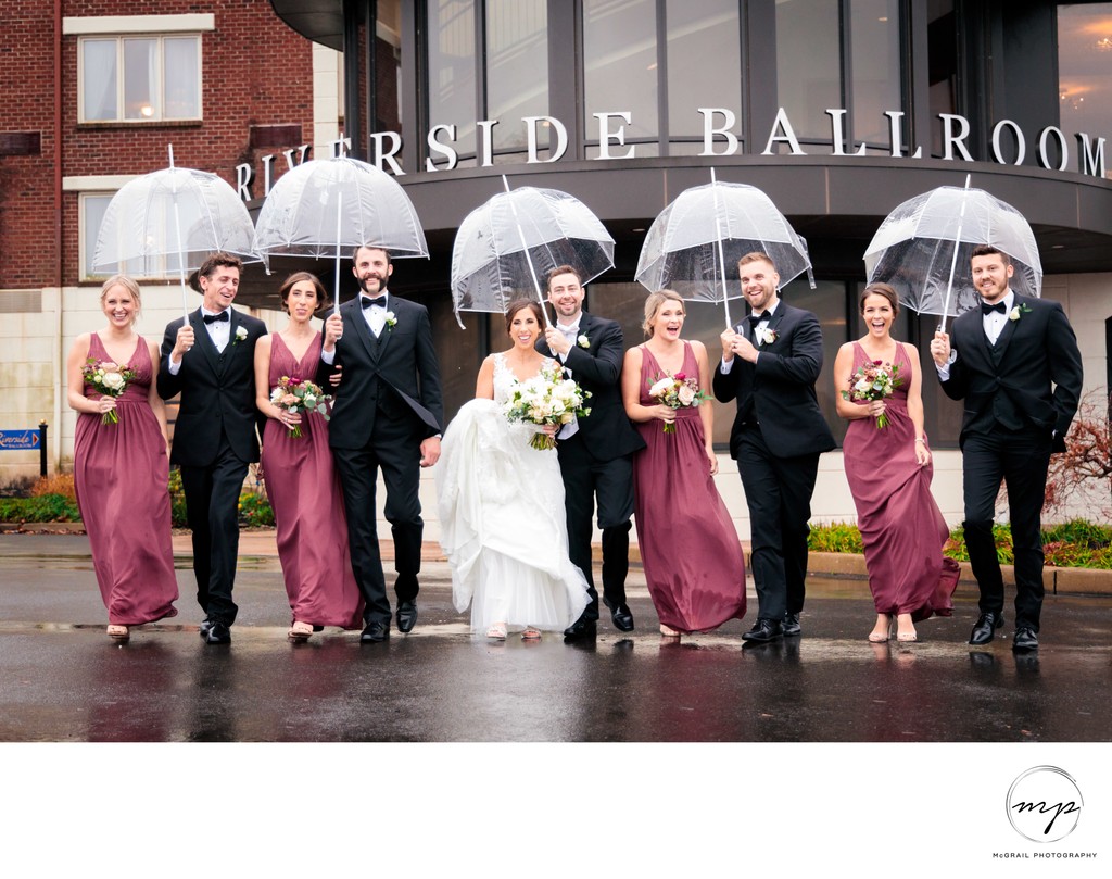 fun bridal party with umbrellas under the rain