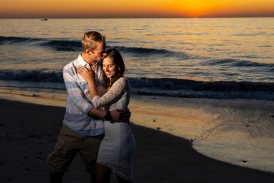 romantic engaged couple by the waves during sunset