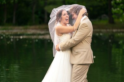 bride and groom laughing under bride's veil