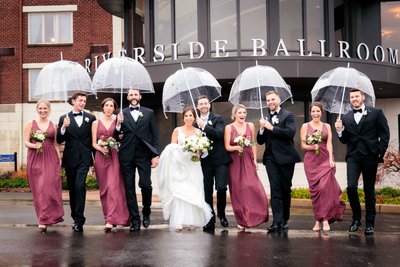 fun bridal party with umbrellas under the rain