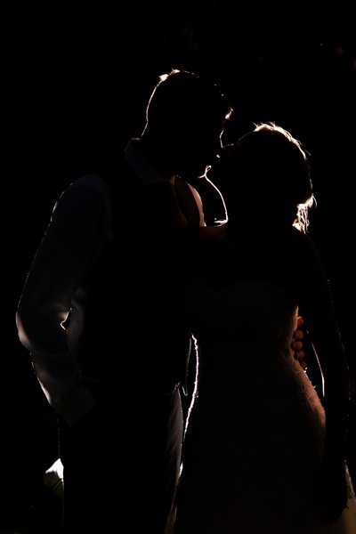 Silhouette of Bride and Groom Sharing a Kiss