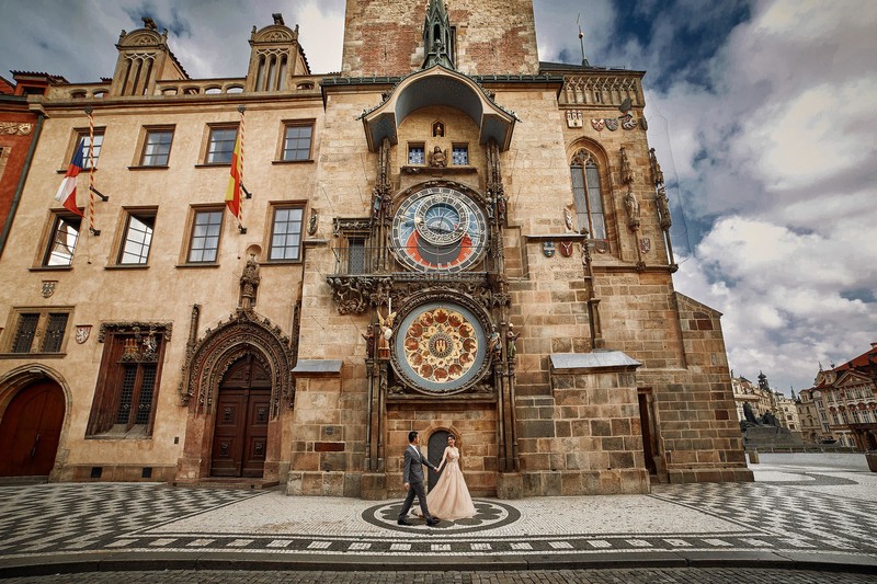 Couple walking in an empty Prague underneath the Orloj