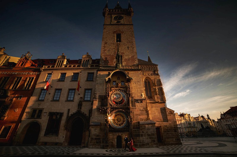 Elegant couple walking under Prague Astronomical Clock 