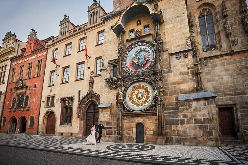 Bride & groom running underneath the Astronomical Clock in Prague