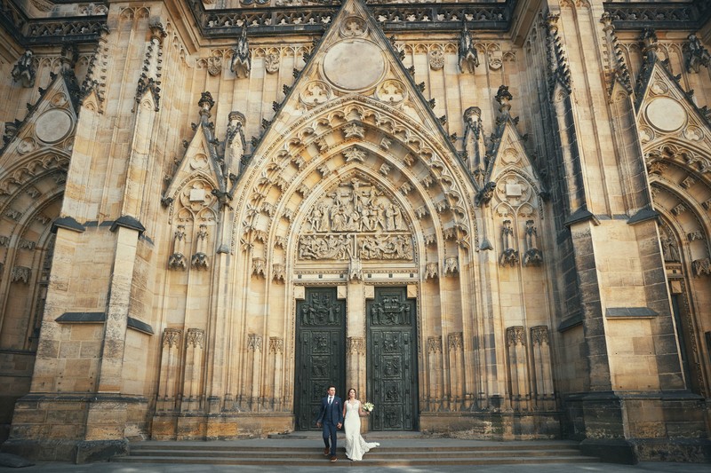 Bride & Groom happily walking underneath Prague St. Vitus Cathedral