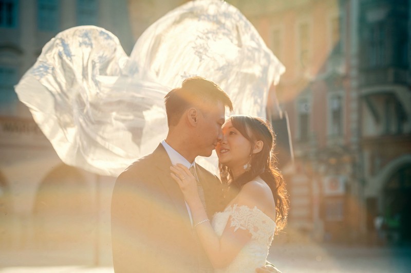 Bride & groom embrace as the veil flies above in the golden sunlight