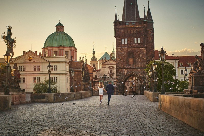 American couple running across the Charles Bridge