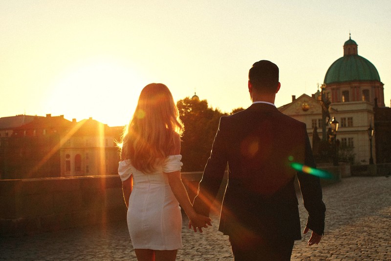 Sexy Californians walking hand-in-hand across Charles Bridge at sunrise