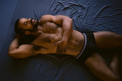 Man in underwear laying on back in grey bed