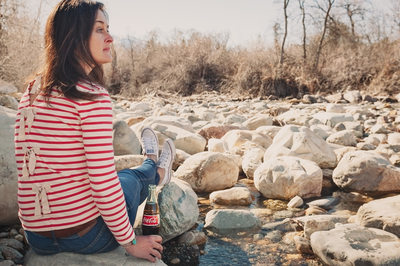 Woman with Coca Cola bottle at edge of a rocky creek