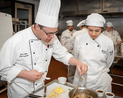 Chef trains culinary student in preparing Asian food