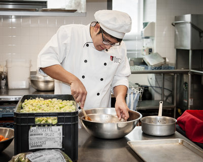 Culinary student stirs a stainless steel bowl