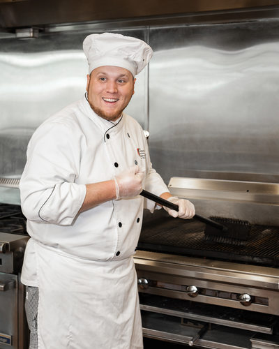 Student chef prepares the grates for grilling