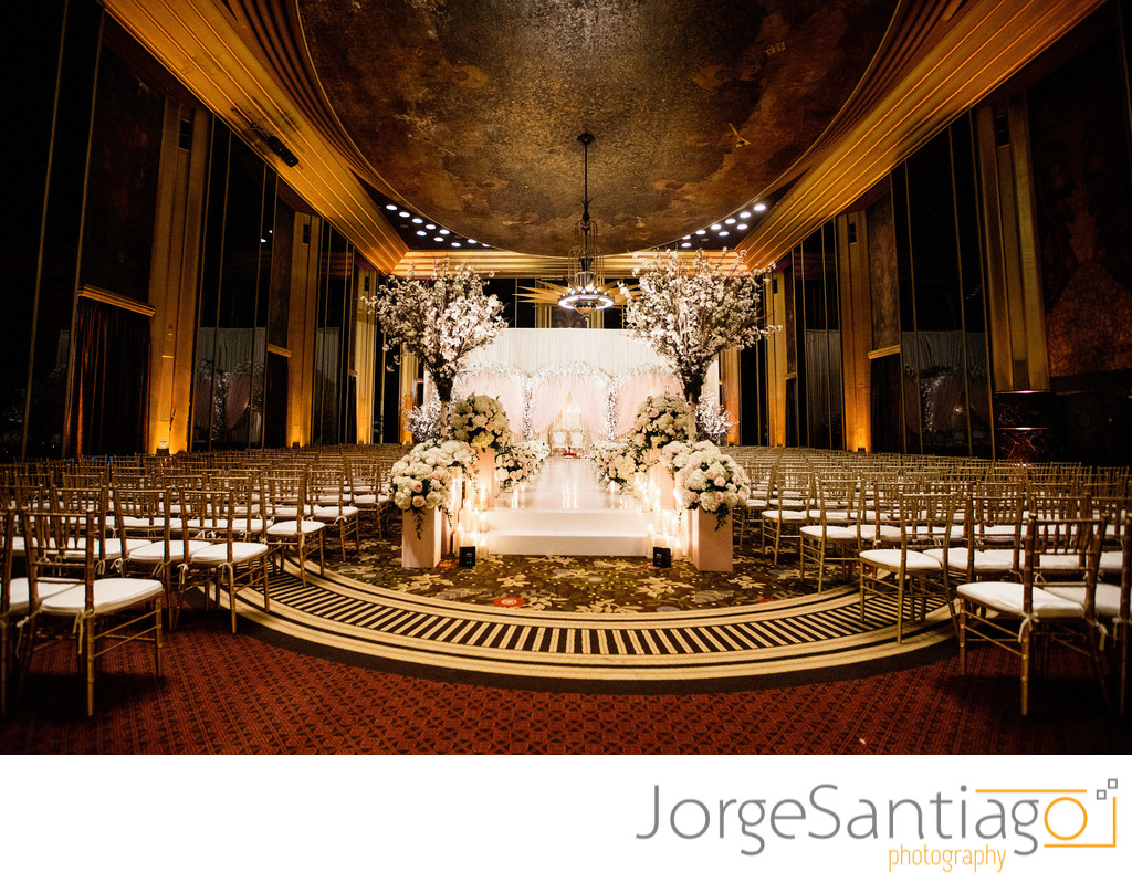 elaborate flower and candle stage in elegent venue with gold accents 