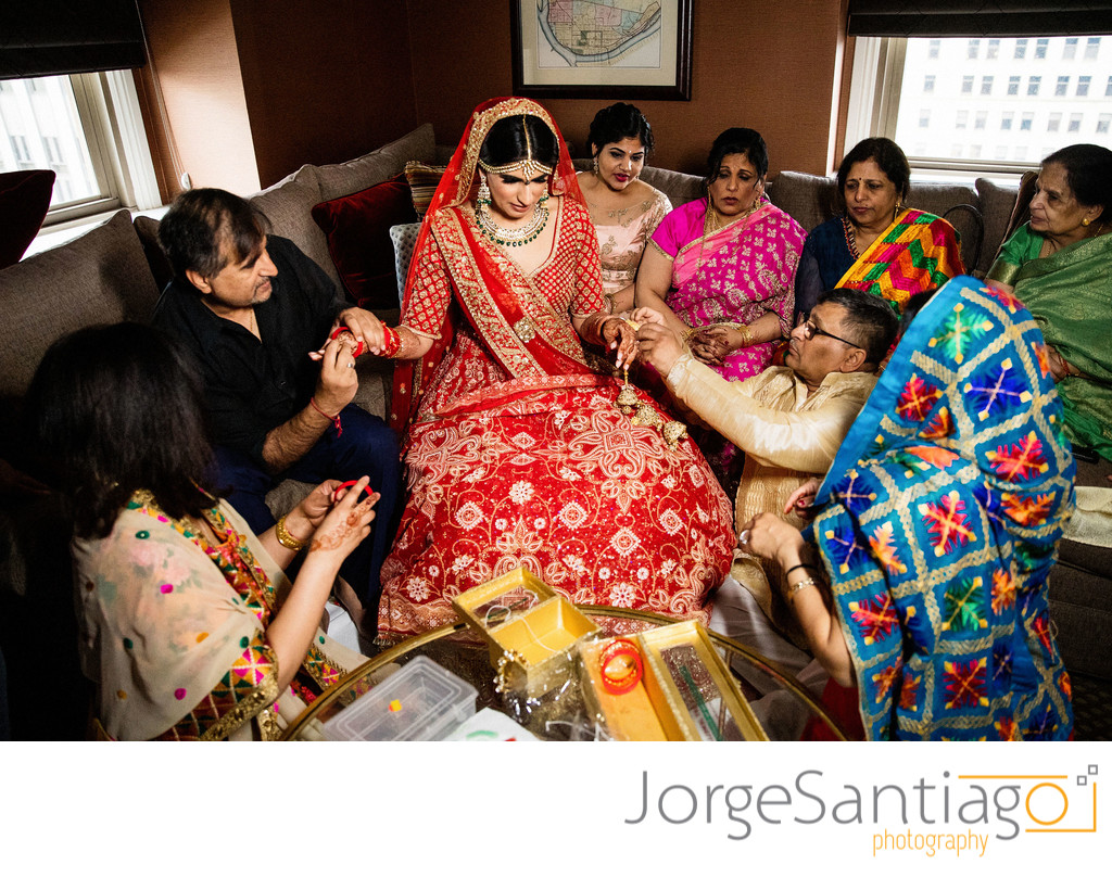 south asian indian bride dressed in red receiving gifts from family 