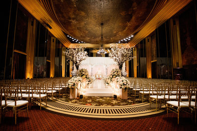 elaborate flower and candle stage in elegent venue with gold accents 